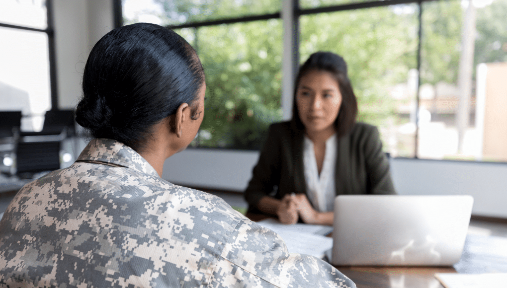 A job interviewer speaks to a job applicant in military fatigues.