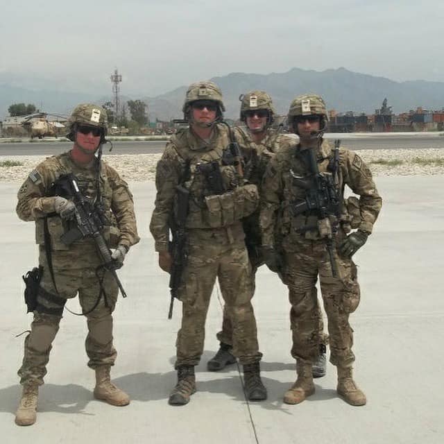 Florent Groberg and three other men stand facing the camera in their army uniforms.