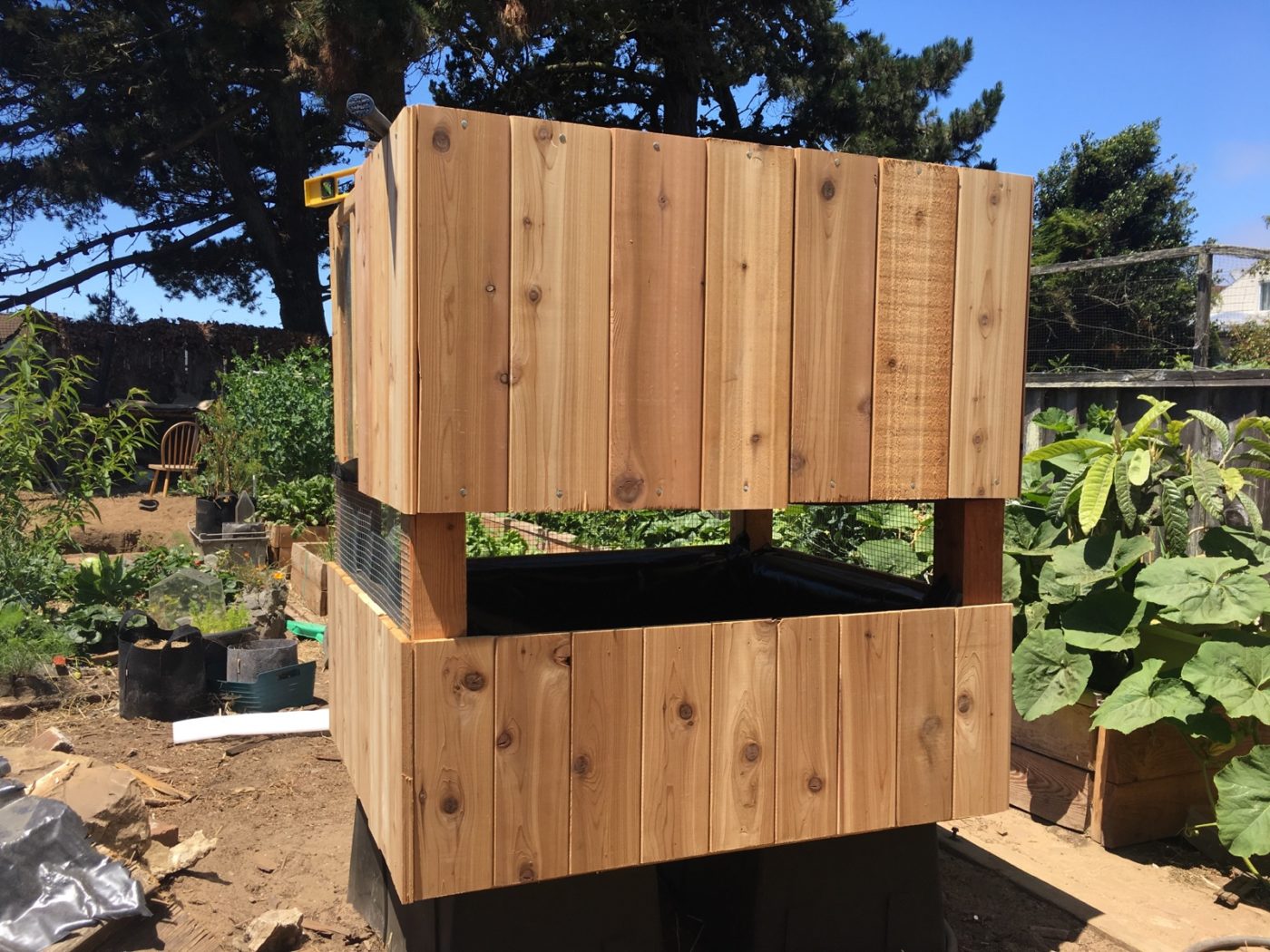 Two wooden structures stack on top of each other in a garden.