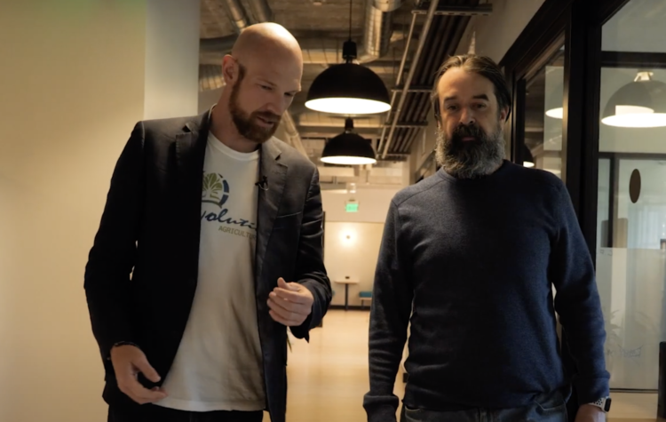 Richard Brion walks down a hallway next to another man with a beard.