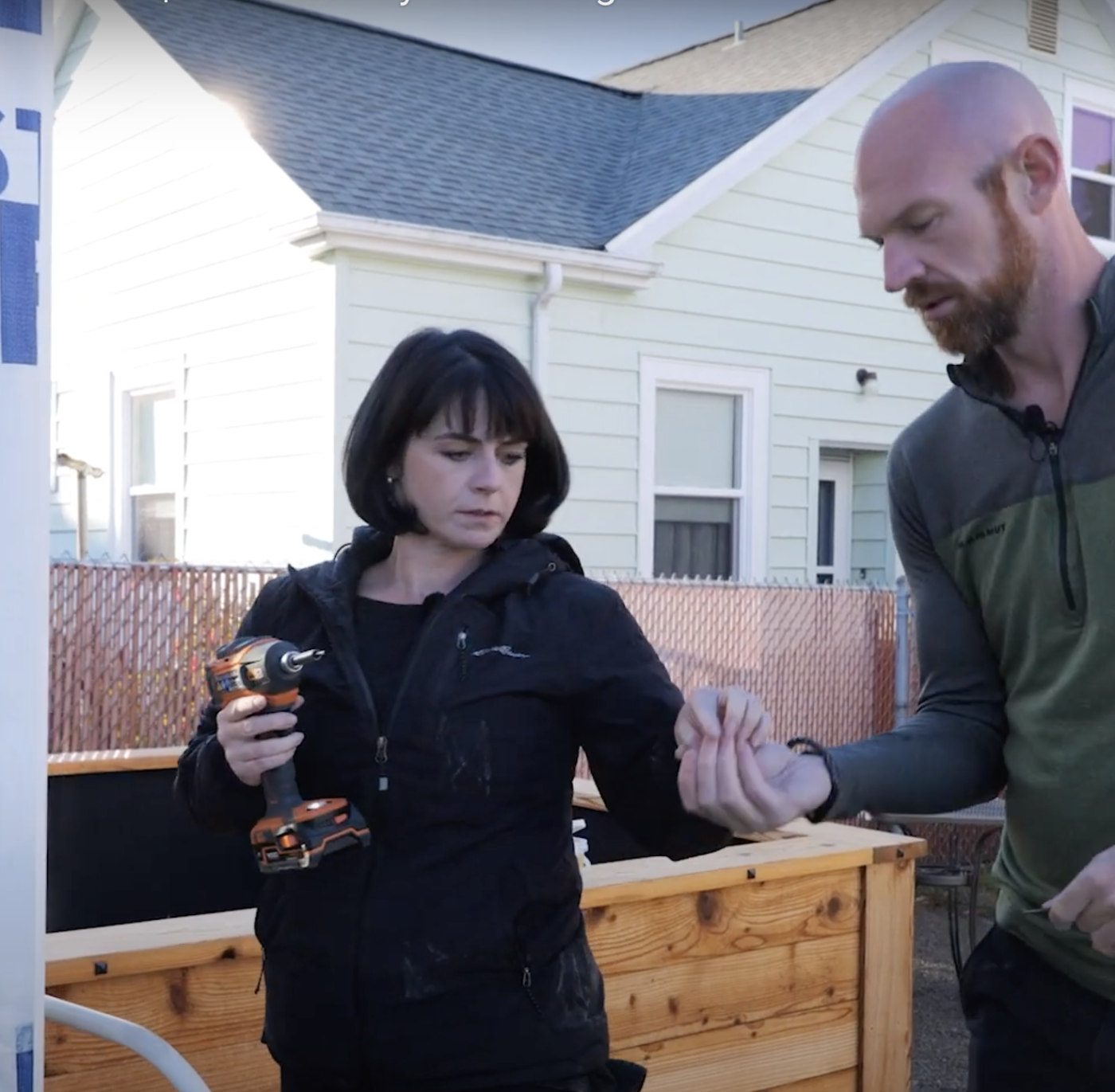 Richard Brion hands a screw to a woman holding a drill.
