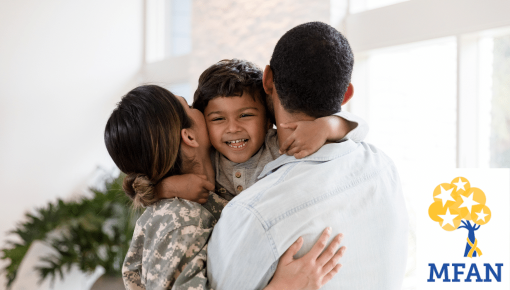 A man in civilian clothing and a woman in a military uniform hug a young child.