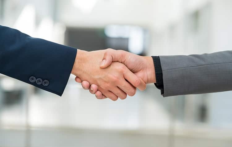 Close-up image of a handshake between two people wearing suit jackets.