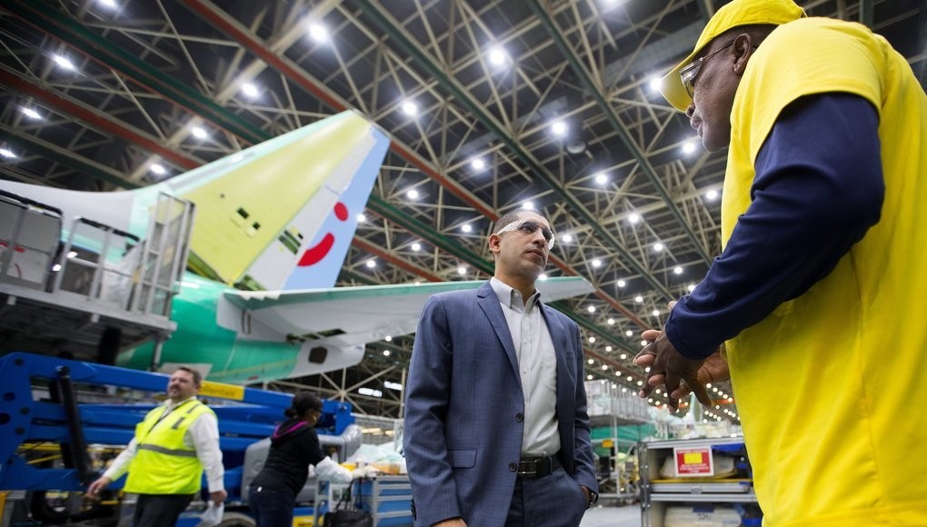 Florent Groberg stands in front of a Boeing airplane, facing a man in a yellow shirt and yellow hat.