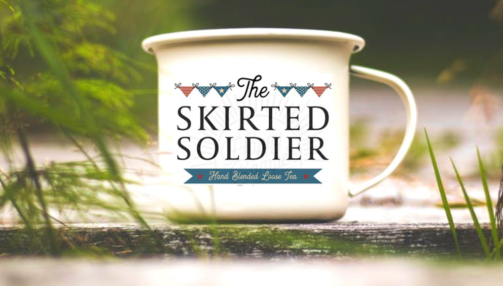 A mug that says "The Skirted Soldier" sits on the ground outside.