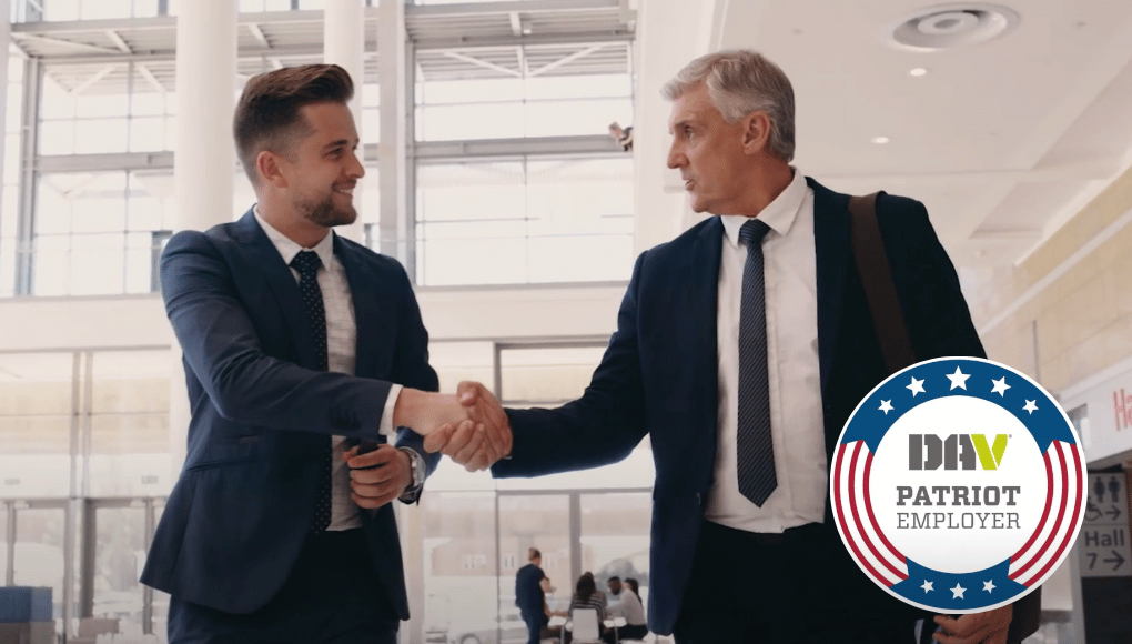 Two men shake hands in suits and ties.